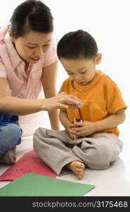 Asian boy and mother coloring with crayons.