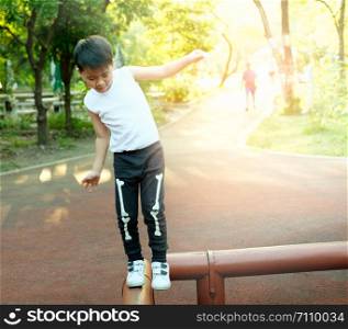 Asian boy balancing on timber In the park.