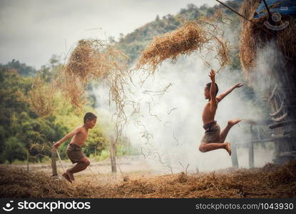 Asian boy friend children happy funny jump and playing rice straw at agricultural farm in the countryside of living life kids rural people