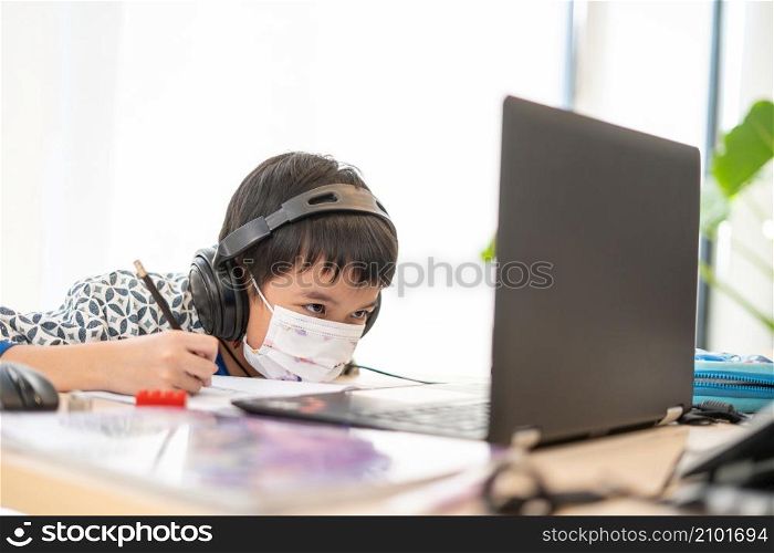 Asian boy happy using Laptop computer studying online at home during home quarantine epidemic problem ,chat friend or teacher or parent via computer. homeschooling, online study, online learning, corona virus or technology concept