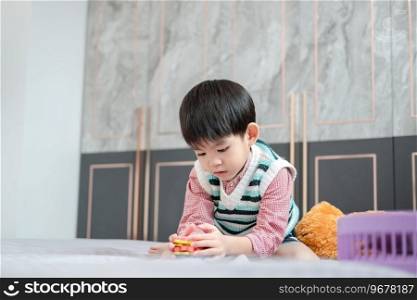 Asian boy playing with jigsaw puzzles on the bed joyfully