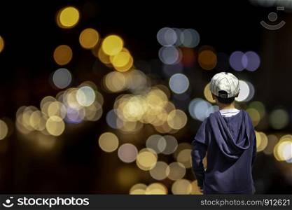 Asian boy see blurred lights of the house and street light, bright beautiful.