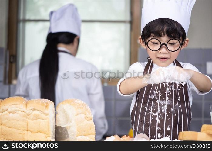 Asian Boy wear glasses cooking with white flour Kneading bread dough teaches children practice baking ingredients bread, egg on tableware in kitchen lifestyle happy Learning life with family Fun to learn