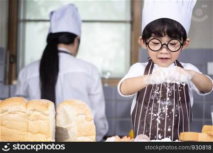 Asian Boy wear glasses cooking with white flour Kneading bread dough teaches children practice baking ingredients bread, egg on tableware in kitchen lifestyle happy Learning life with family Fun to learn