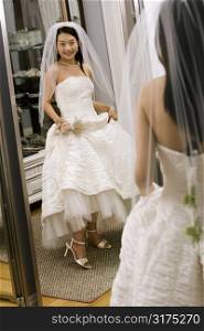 Asian bride admiring shoes in mirror.
