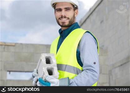 asian builder man holding concrete blocks for house building