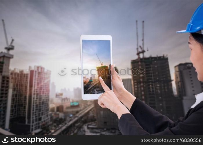Asian business engineer architecture professional woman, wearing safety helmet and use smartphone to capture construction site for working and presenting job concept