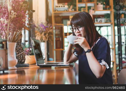 Asian business female working with laptop make a note in coffee shop like the background.