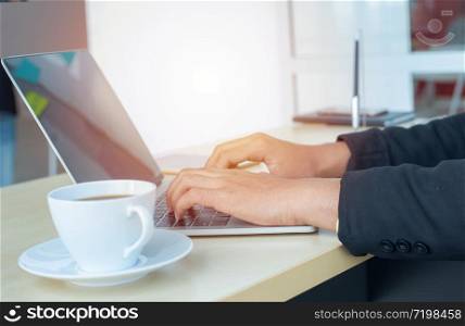 Asian business man hands typing on laptop computer keyboard with business graph diagram data paperwork ,mobile phone and cup of coffee on the desk at modern home office. Digital marketing concept.