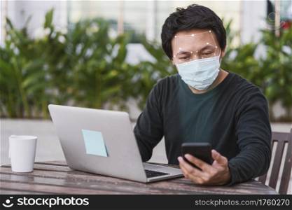 Asian business man in casual clothes using mobile phone for biometric scan and face detection when working at home,Technology and new normal Covid-19 outbreak, social distancing concept