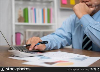 Asian business man use a calculator To calculate income And expenses for profit and loss for annual summary report. The concept of Business success Need to be analyzed And management planning.