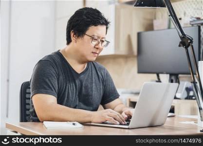 Asian business man using technology laptop for working from home in indoor bedroom of house by video conference call, startups and business owner,lifestyle occupation,social distancing concept