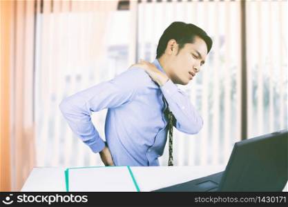 Asian Business men with back pain sin an office and serious about the work done until the headache on working hard