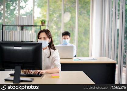 Asian business people with medical mask for virus protection working in office. new normal and social distancing concept.