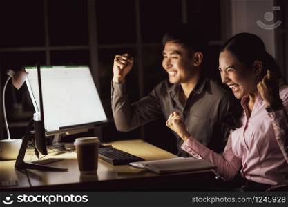 Asian business woman and business man working hard late together with technology computer in office,team work with colleagues to congratulations for success achievement project concept