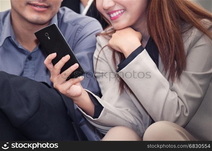 Asian business woman and man smiling and using cell phone together