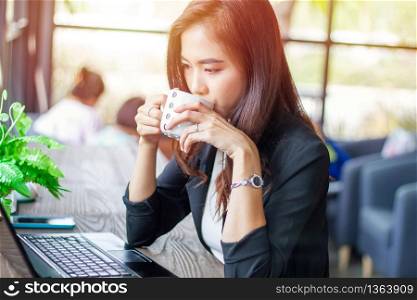 Asian business woman is working and drinking coffee at coffee shop on relax time