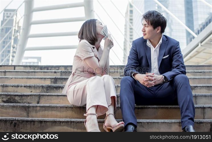 Asian business woman kissing banknotes after her boyfriend surprising her by a lot of money.