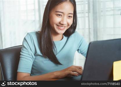 Asian business woman using laptop at office, Asian girl sitting smiling while working on mobile office concept