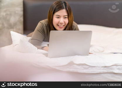 Asian business woman using technology laptop and working from home in indoor bedroom,freelance and entrepreneur,startups and business owner,lifestyle occupation,social distance and self responsibility