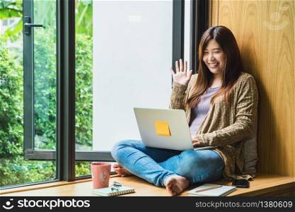 Asian business woman using technology laptop and working from home with say hello or bye, freelance and entrepreneur, creative design and blogger, social distance and self responsibility concept
