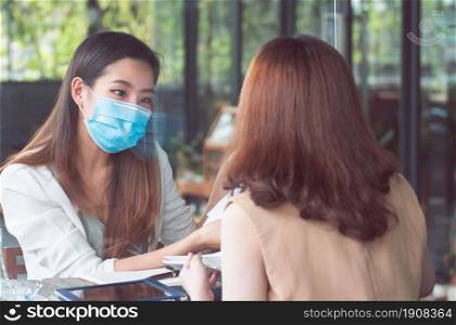 Asian business woman wearing mask and keeping social distancing while working. New Normal and Business Concept.