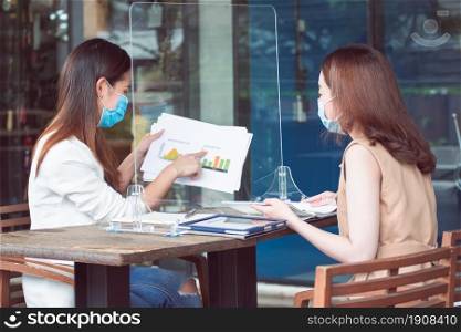 Asian business woman wearing mask and keeping social distancing while working. New Normal and Business Concept.