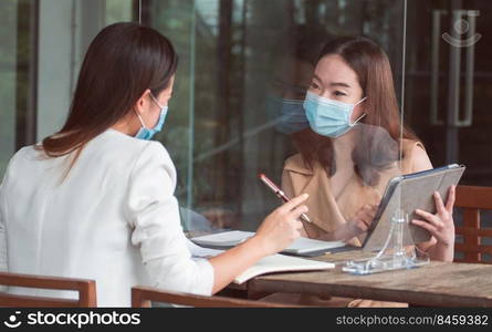 Asian business woman wearing mask and keeping social distancing while working. New Normal and Business Concept.