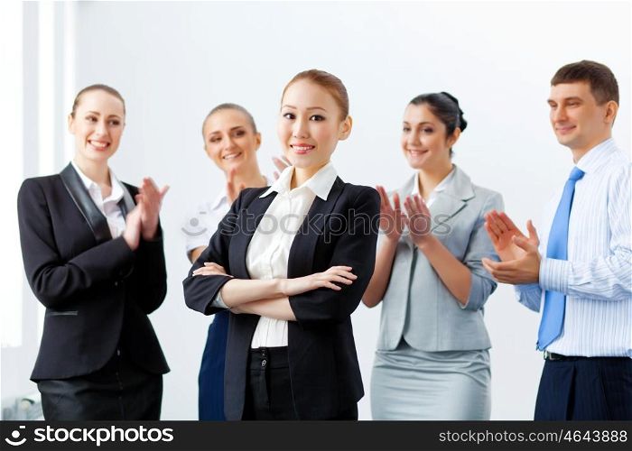 Asian business woman with colleagues. Young asian businesswoman smiling with colleagues applauding joyfully at background