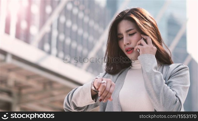 Asian business woman worried about time because she nearly late appointment with her important meeting which represent concept of work in rush hours workday and outdoor working in modern city