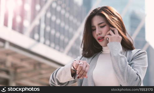 Asian business woman worried about time because she nearly late appointment with her important meeting which represent concept of work in rush hours workday and outdoor working in modern city