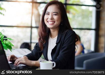 Asian business women smiling and using notebook for working at coffee cafe