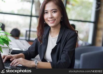 Asian business women using notebook and business women smiling happy for working ,soft focus