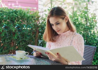 Asian business women working and writing a book and checking document at outdoor ,soft focus