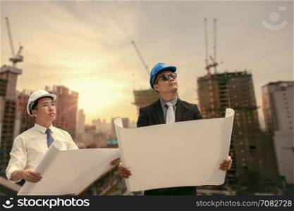Asian businessman and engineer architect professional occupation corporate city looking away and holding construction idustrial plan for working concept