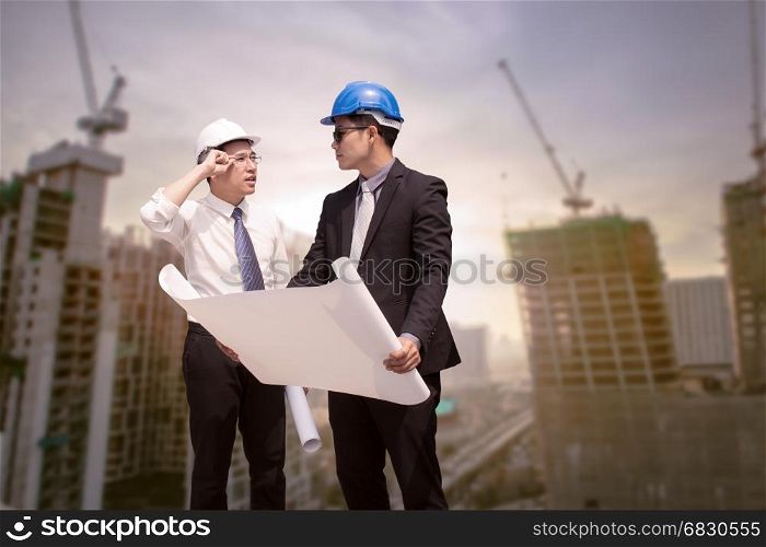 Asian businessman discuss with engineer architect professional occupation corporate city looking away and holding construction idustrial plan for working concept