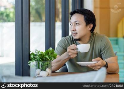 Asian businessman drinking and working from home in happiness feeling at desk beside the glass in modern coffee shop or office,Business owner and entrepreneur concept