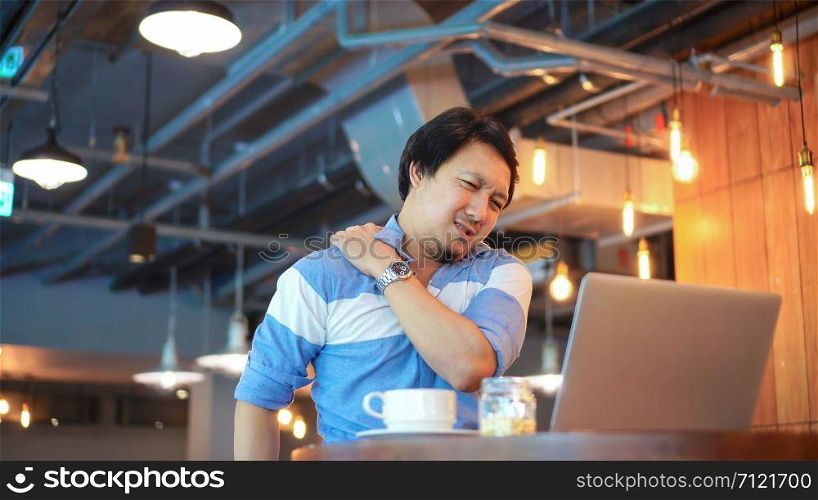 Asian businessman in casual suit working which have symptom is Neck pain, backache, headache at co-working space, office syndrome concept
