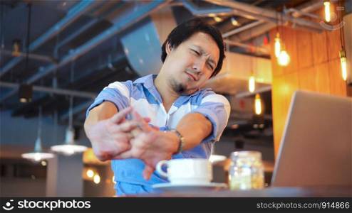 Asian businessman in casual suit working which have symptom is Neck pain, backache, headache at co-working space, office syndrome concept