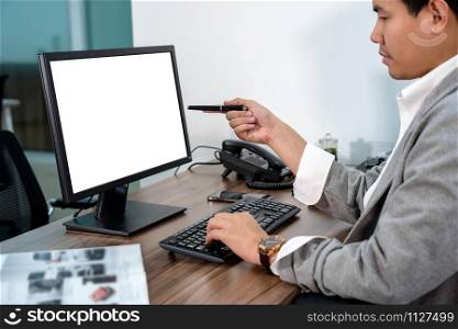 Asian Businessman in formal suit using and pointing the pen to computer screen in office, business and technology workplace concept