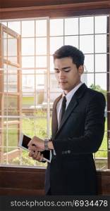 asian businessman looking at wrist watch. asian businessman holding tablet and looking at wrist watch
