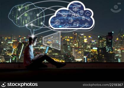 Asian businessman sitting and using the laptop and working with brain and virtual screen connecting with cloud technology over the cityscape background at night time, Business and technology concept