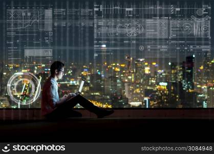 Asian businessman sitting and using the laptop showing digital virtual screen over the cityscape background at night time, Business technology and innovation concept