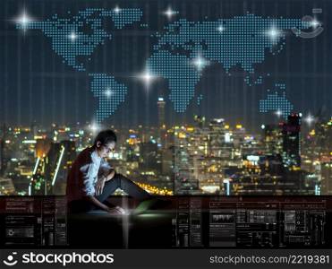 Asian businessman sitting and using the laptop with Network graphic over the world map dot and cityscape background at night time, Business success and technology concept