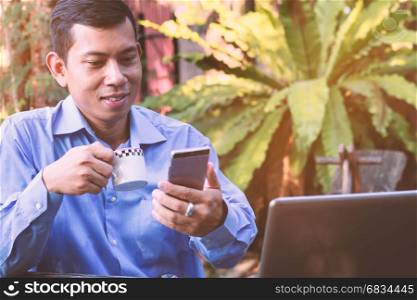 Asian businessman smiles while receiving a text message from the smartphone.Vintage Style.