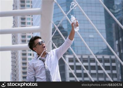 Asian Businessman standing and happy to drink water and hold bottle and modern city background