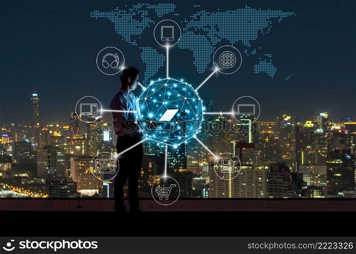 Asian businessman standing and using the laptop for online shopping with omni channel over the cityscape background at night time, Business success and technology concept