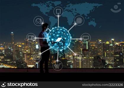 Asian businessman standing and using the laptop for online shopping with omni channel over the cityscape background at night time, Business success and technology concept