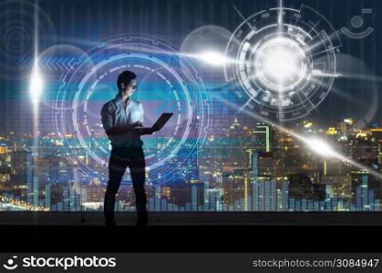 Asian businessman standing and using the smart mobile phone showing with technology digital virtual screen over the cityscape background at night time, Business technology and trading concept