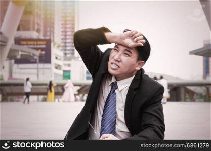 Asian businessman take off the eyeglasses tired and looking up the sun in the modern city for working load concept